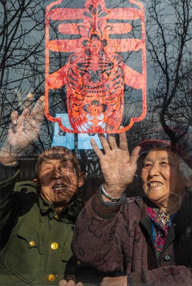 臘月里，霍州市師莊鄉(xiāng)馮南垣村村民師榮光(左)在災后重建的新家里貼窗花。(霍州市委宣傳部供圖)