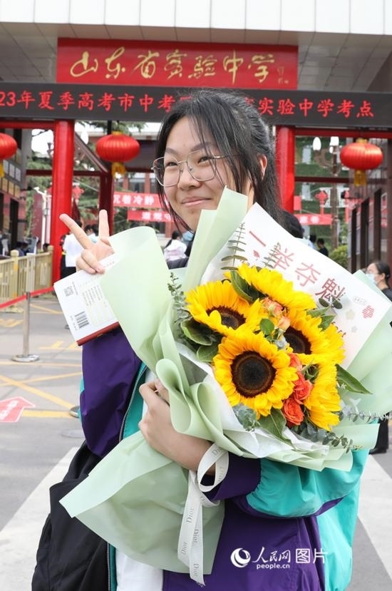 6月7日高考首日，山東67萬考生走進考場，拼搏逐夢。在山東省實驗中學考點，考生進考場前手捧向日葵花拍照留念，寓意“一舉奪魁”。人民網(wǎng)記者 劉祺攝