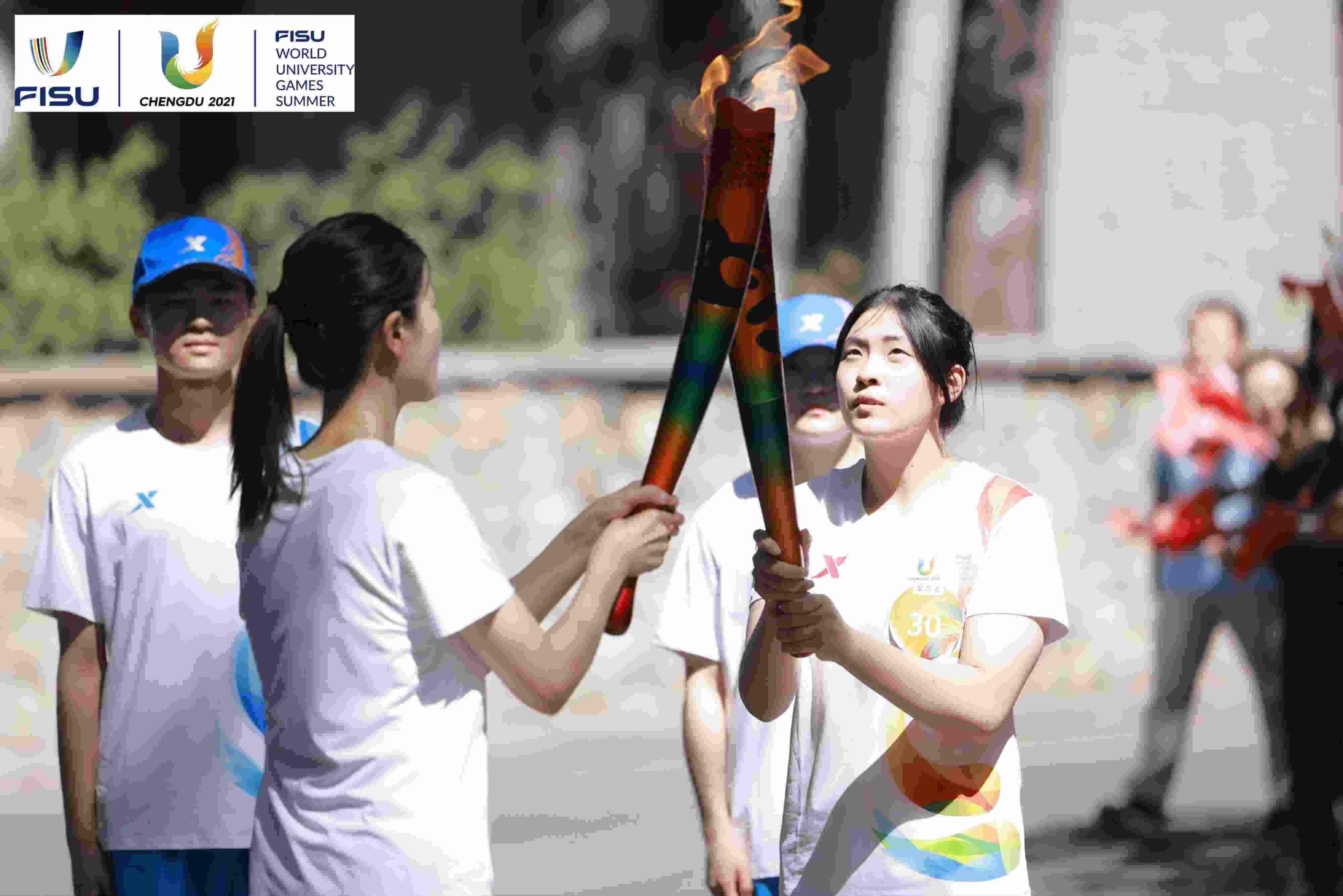 兩名大運(yùn)會火炬手進(jìn)行火炬?zhèn)鬟f。 圖片來源：成都大運(yùn)會執(zhí)委會供圖