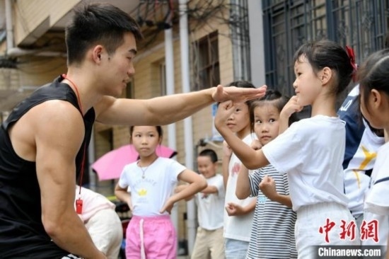 圖為大學(xué)生志愿者在組織孩子們參加體育健身活動。廖光福 攝