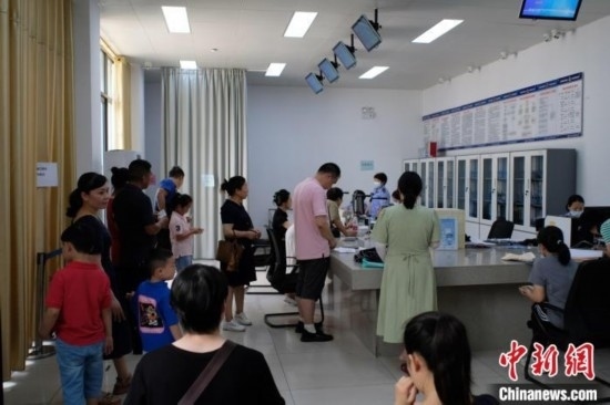 圖為在戶籍辦證廳內(nèi)排隊(duì)等待的家長和孩子。劉俊聰 攝