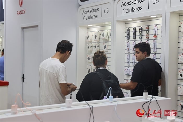 幾名參觀者在一個展臺前了解手機(jī)配件。（人民網(wǎng)記者 時元皓攝）