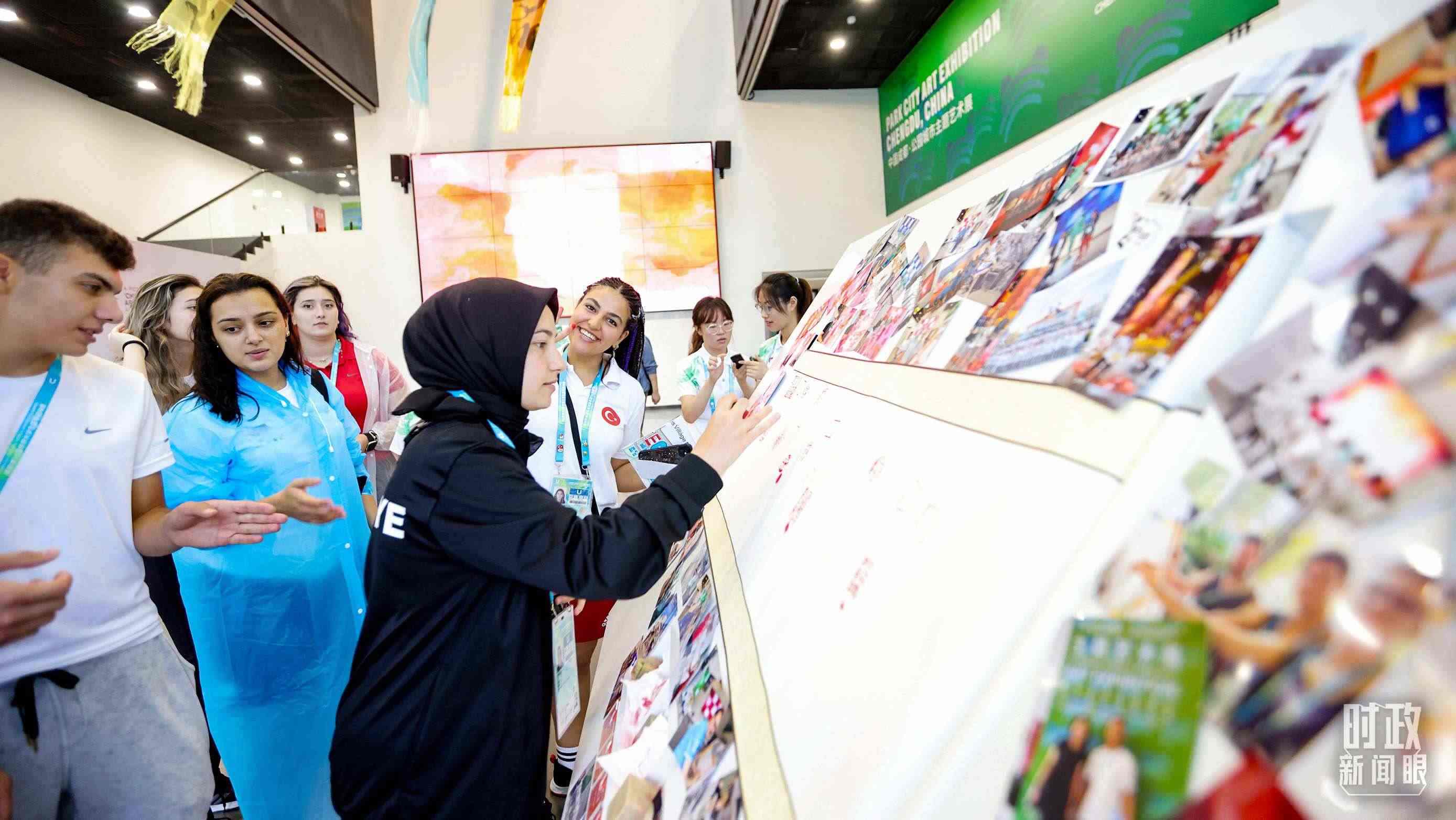 各國青年運(yùn)動員正在參觀成都大運(yùn)村內(nèi)的“雪山下的公園城市，煙火里的幸福成都”主題藝術(shù)展。（總臺央視記者魏幫軍拍攝）