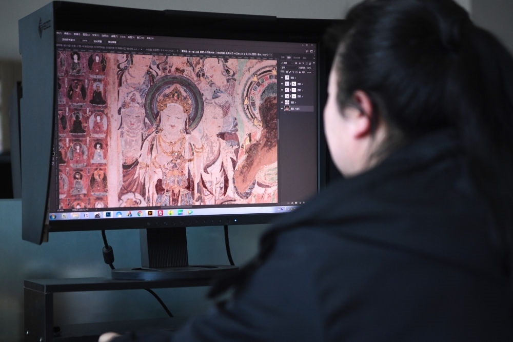 敦煌研究院文物數(shù)字化保護團隊圖像處理人員年海麗在拼接壁畫圖像（2023年4月25日攝）。數(shù)字化探索為莫高窟的保護與傳承開辟了全新路徑，數(shù)字技術讓敦煌文物走出洞窟，跨出國門，走向“永久保存、永續(xù)利用”。新華社記者 陳斌 攝