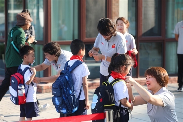 8月30日，雄安史家胡同小學(xué)學(xué)生體驗(yàn)學(xué)校生活。老師為學(xué)生佩戴校徽。