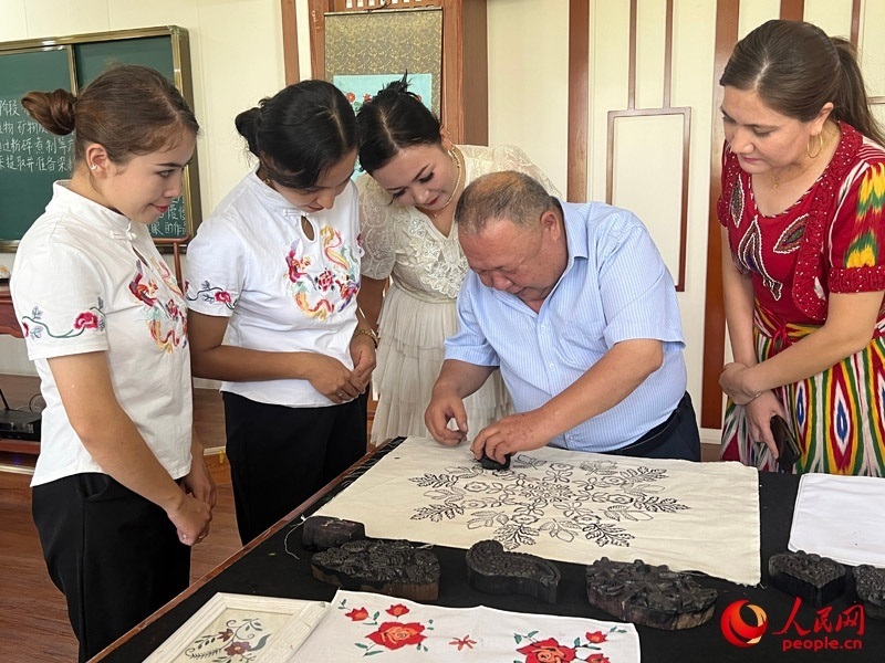 國家級非物質(zhì)文化遺產(chǎn)模戳印花布技藝傳承人吾吉阿西木?吾舒爾展示模戳印花布的制作過程。人民網(wǎng)記者 常雪梅攝