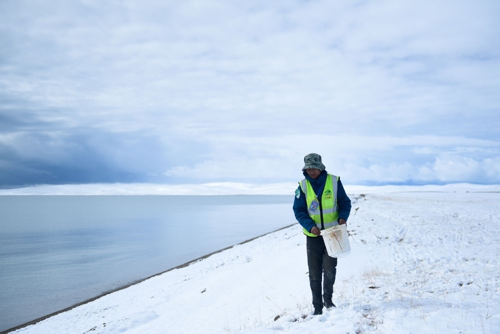 2021年10月20日，在青海省果洛藏族自治州瑪多縣扎陵湖鄉(xiāng)勒那村，三江源國家公園黃河源園區(qū)生態(tài)管護員在扎陵湖邊撿拾垃圾。新華社記者 張龍 攝