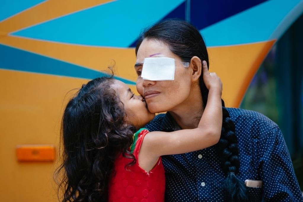 2019年3月15日，在柬埔寨磅湛省醫(yī)院，即將接受白內(nèi)障手術(shù)的患者孫美樂接受女兒的親吻祝福。在接受了中國醫(yī)療隊的白內(nèi)障義診手術(shù)后，她的視力逐步恢復(fù)，生活有了新的光明和希望。