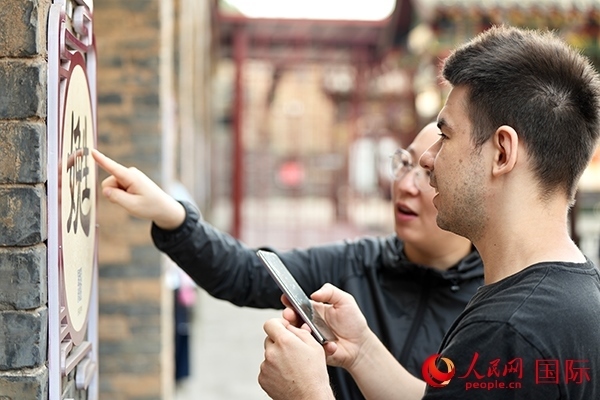 選手安德烈（俄羅斯）在老師指導(dǎo)下學(xué)習(xí)墻壁上張貼的生僻字。人民網(wǎng) 盧鵬宇攝