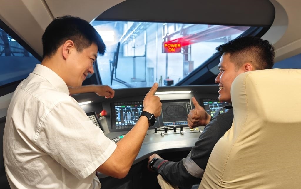 8月25日，在印度尼西亞萬隆的雅萬高鐵德卡魯爾動車所內(nèi)，中國師傅穆振（左）在向印尼火車司機塞蒂亞萬講解動車組出庫前的上電作業(yè)。