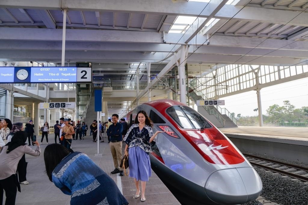 10月17日，在印度尼西亞萬隆德卡魯爾站，乘客在站臺上和雅萬高鐵高速動車組列車合影。
