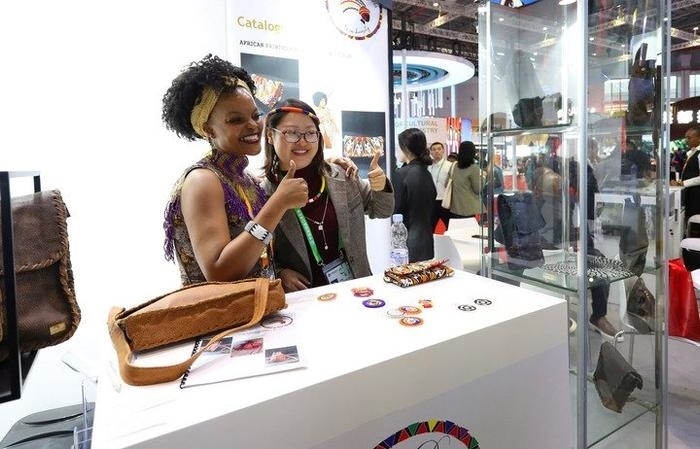 11月6日，一位參觀者（右）在第六屆進(jìn)博會國家展南非展臺試戴傳統(tǒng)首飾。