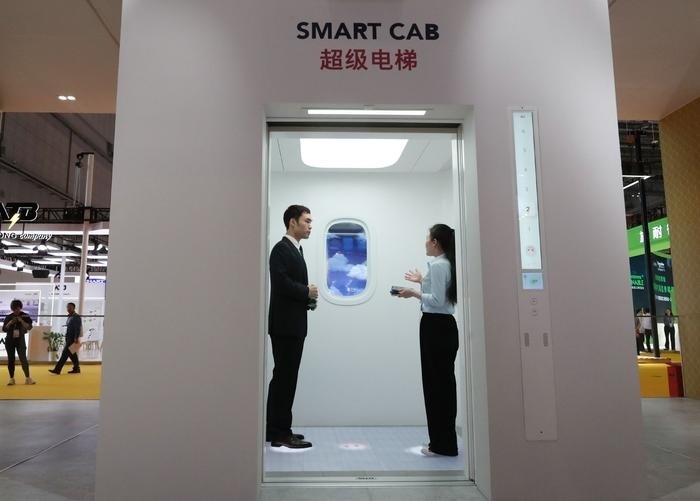 11月5日，工作人員（右）在第六屆進(jìn)博會上向參觀者介紹奧的斯公司全新推出的超級電梯。