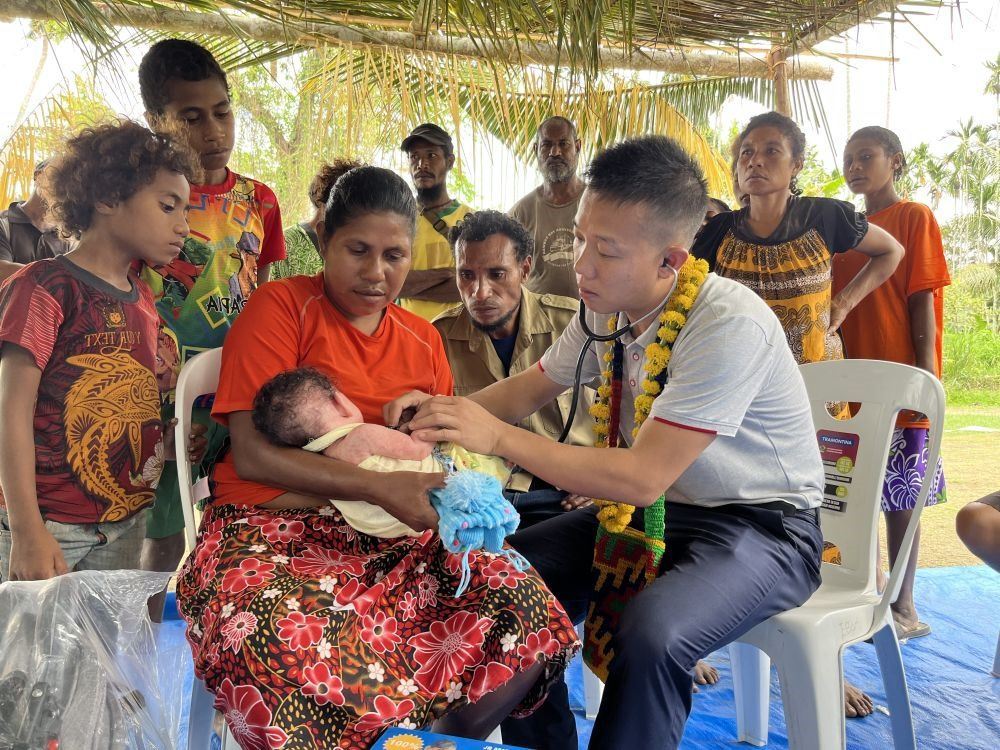 2023年8月5日，在巴布亞新幾內亞中央省的一個村莊里，第12批援巴新中國醫(yī)療隊副隊長、新生兒科副主任醫(yī)師劉振球為嬰兒泰樂聽診檢查。泰樂出生時患有重癥，一度生命垂危，經(jīng)過劉振球與當?shù)蒯t(yī)護人員的救治最終痊愈。從2002年起，中國連續(xù)向巴新派出12批醫(yī)療隊，為提高巴新醫(yī)療衛(wèi)生水平作出積極貢獻。