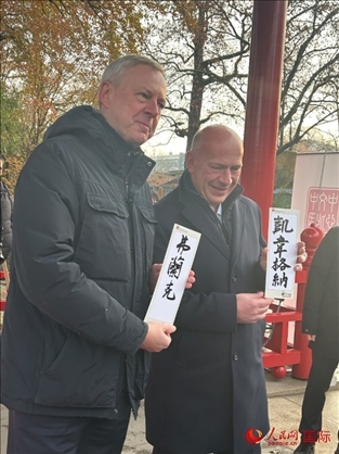 柏林市長韋格納（右）、動物園監(jiān)事會主席布魯克曼（左）手持中國文化中心工作人員現(xiàn)場手書的中文名字。人民網(wǎng)記者 徐馨攝