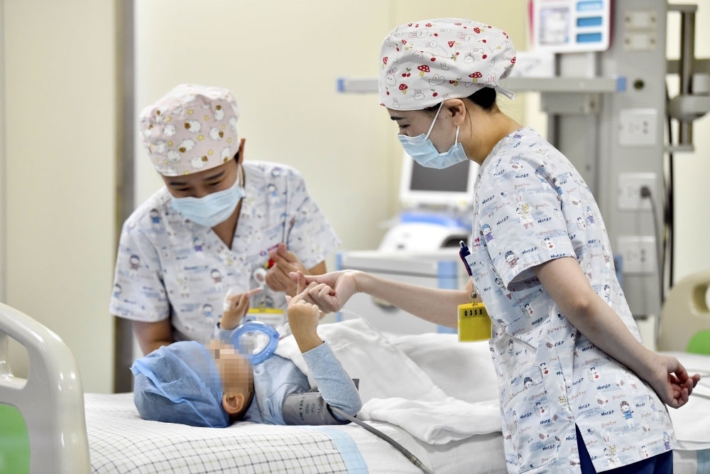 在山東省棗莊市婦幼保健院兒童ICU病房，醫(yī)護人員為完成靶向治療藥物諾西那生鈉的4歲脊髓性肌萎縮癥患兒加油鼓勁（2022年1月1日攝）。諾西那生鈉注射液是我國首個獲批治療脊髓性肌萎縮癥的進口藥物，2019年進入中國市場時，每針價格近70萬元。在2021年國家醫(yī)保目錄藥品談判中，以3.3萬元每針的價格進入新版醫(yī)保藥品目錄。新華社記者 郭緒雷 攝