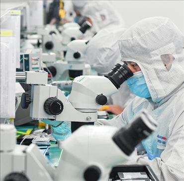 在位于武漢中國(guó)光谷的光電器件研發(fā)制造商——武漢光迅科技股份有限公司生產(chǎn)車(chē)間內(nèi)，技術(shù)人員在光模塊生產(chǎn)線作業(yè)（2023年4月11日攝）。程敏攝/本刊