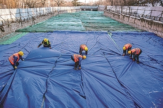 1月3日，房山區(qū)東風(fēng)街道，工人正在修復(fù)的河道內(nèi)給混凝土鋪設(shè)保溫布。