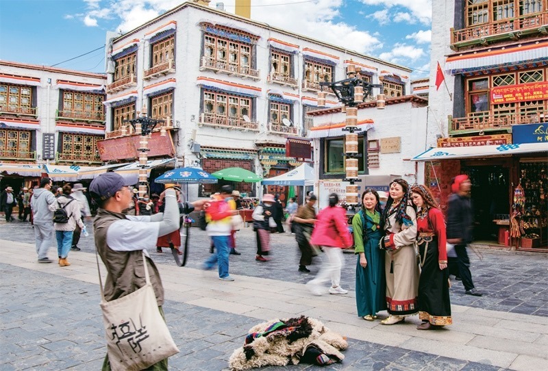 千年八廓街，見(jiàn)證民族團(tuán)結(jié)。2021年7月，習(xí)近平總書(shū)記來(lái)到位于西藏拉薩老城區(qū)的八廓街，感慨地說(shuō)：“千年八廓街，是我們各民族建起來(lái)的八廓街。各民族文化在這里交流交往交融，我們中華民族的大家庭在這里其樂(lè)融融?！眻D為2023年6月13日，游客身著藏裝在八廓街拍照留念。 新華社記者 姜帆/攝