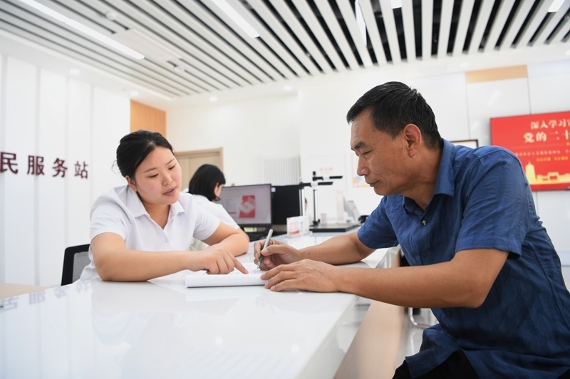 2023年5月23日，河北雄安新區(qū)容東片區(qū)南文營(yíng)社區(qū)居民（右）在社區(qū)便民服務(wù)站辦理業(yè)務(wù)。