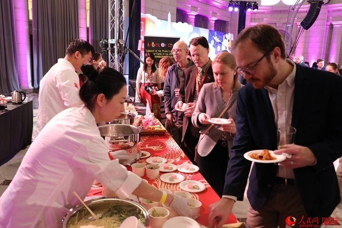 當?shù)貢r間3月7日晚，華盛頓聯(lián)合車站廣場舉行駐美使團“使館主廚挑戰(zhàn)賽”。圖為當?shù)孛癖娫谥袊古_前體驗中國美食。人民網(wǎng)記者 李志偉攝