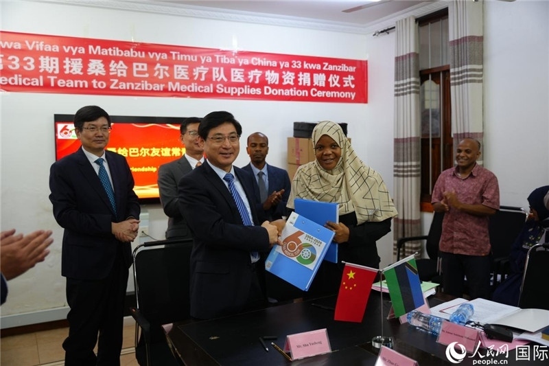 江蘇省蘇北人民醫(yī)院黨委書記束余聲與桑衛(wèi)生部首席秘書哈比巴交換捐贈書。中國援桑醫(yī)療隊供圖