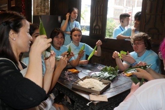 6月9日，美國青年代表在重慶永川松溉古鎮(zhèn)體驗包粽子。新華社記者 周思宇 攝