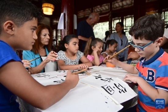 7月4日，在馬耳他桑塔露琪亞市的中國(guó)古典園林“靜園”，人們體驗(yàn)中國(guó)書(shū)法。新華社發(fā)（喬納森·博格 攝）