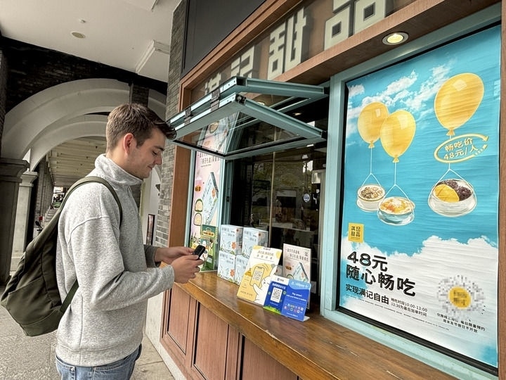 來自德國的留學(xué)生理查德在杭州西湖邊一家商鋪使用支付寶掃碼支付（2024年4月11日攝）。新華社發(fā)