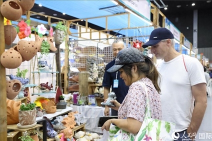 游客在蘭納博覽會特色展位上選購工藝品。人民網(wǎng)記者楊一攝