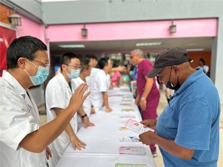 援圭醫(yī)療隊(duì)隊(duì)員們?cè)趩?dòng)儀式上為當(dāng)?shù)孛癖姺职l(fā)宣傳手冊(cè)。中國(guó)援助圭亞那醫(yī)療隊(duì)供圖