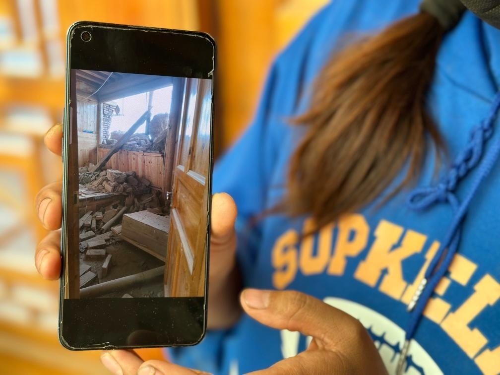 圖為7月17日拉毛東智在手機上找出地震后房屋受損的照片。新華社記者 張子琪 攝