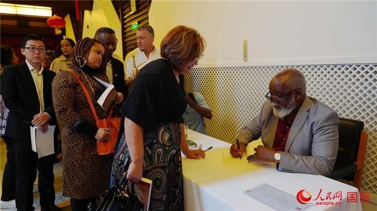 譚哲理在活動現(xiàn)場簽名贈書。人民網 劉暢攝