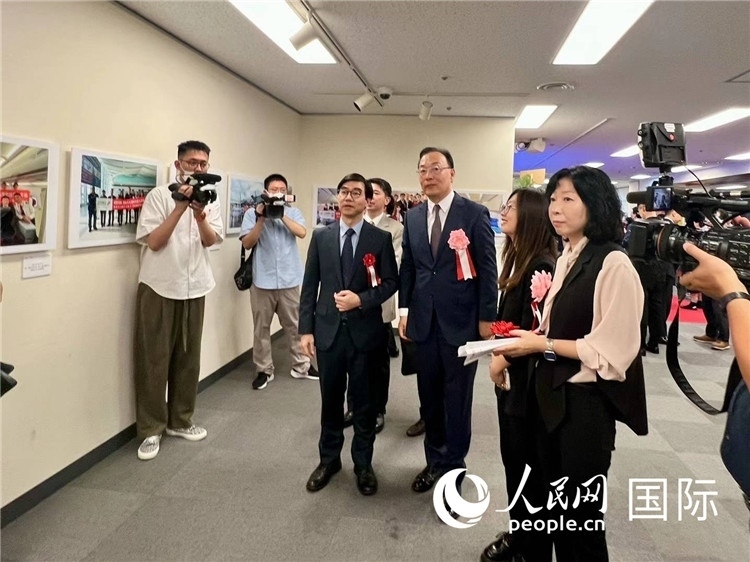 中國(guó)國(guó)際航空日韓地區(qū)支社支社長(zhǎng)馮力為中國(guó)駐日本大使館臨時(shí)代辦施泳等嘉賓介紹展出圖片。人民網(wǎng) 許可攝