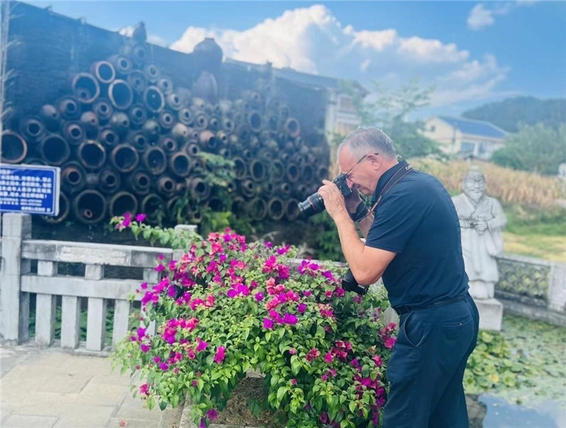 遠處黔北民居錯落有致，近處一只黑色的蝴蝶穿梭于粉紫色三角梅花叢間隙，與俄羅斯“大歐亞”總編輯弗拉基米爾·別列日內(nèi)赫的鏡頭玩起了捉迷藏，“你追我逃，不亦樂乎”。（張亞欣攝）