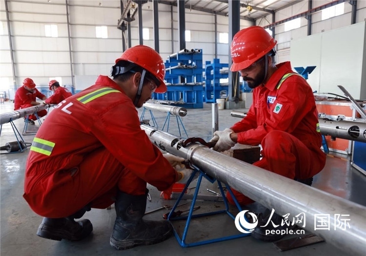 中伊員工共同在檢修鉆井設(shè)備。人民網(wǎng)記者管克江攝