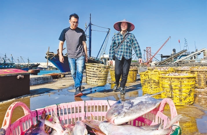 許小斌（左）和漁民一起搬運(yùn)海鮮。本報(bào)記者 付 文攝