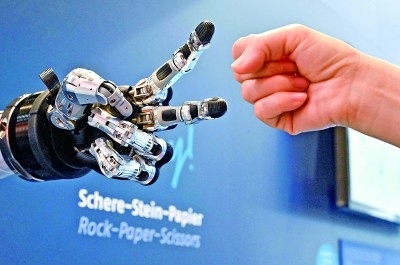 在德國漢諾威工博會上，參觀者與一款智能機器人進行“石頭剪子布”游戲。新華社發(fā)