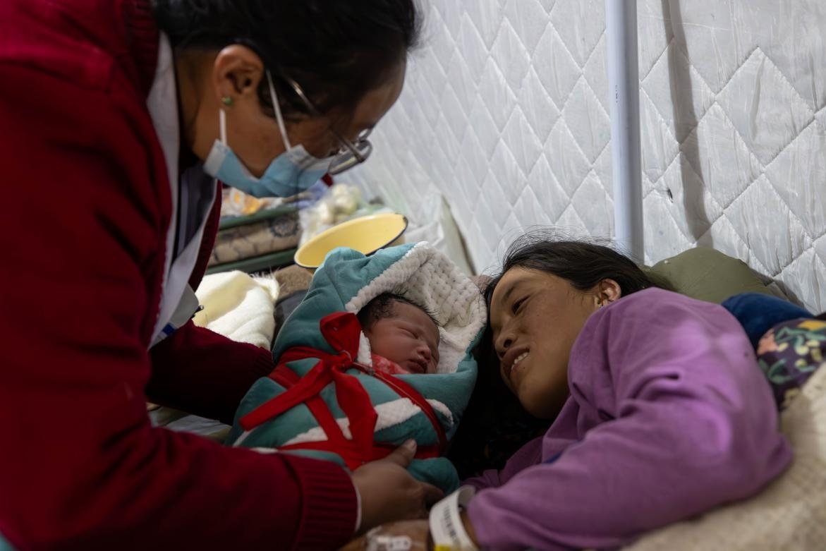 1月10日，定日縣中心醫(yī)院的婦產(chǎn)科醫(yī)生悉心照看一位母親和她懷里的新生兒。人民日?qǐng)?bào)記者張武軍攝