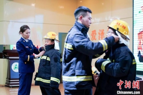 圖為學(xué)生們現(xiàn)場穿戴消防頭盔和戰(zhàn)斗服。中新社記者 趙宇航 攝